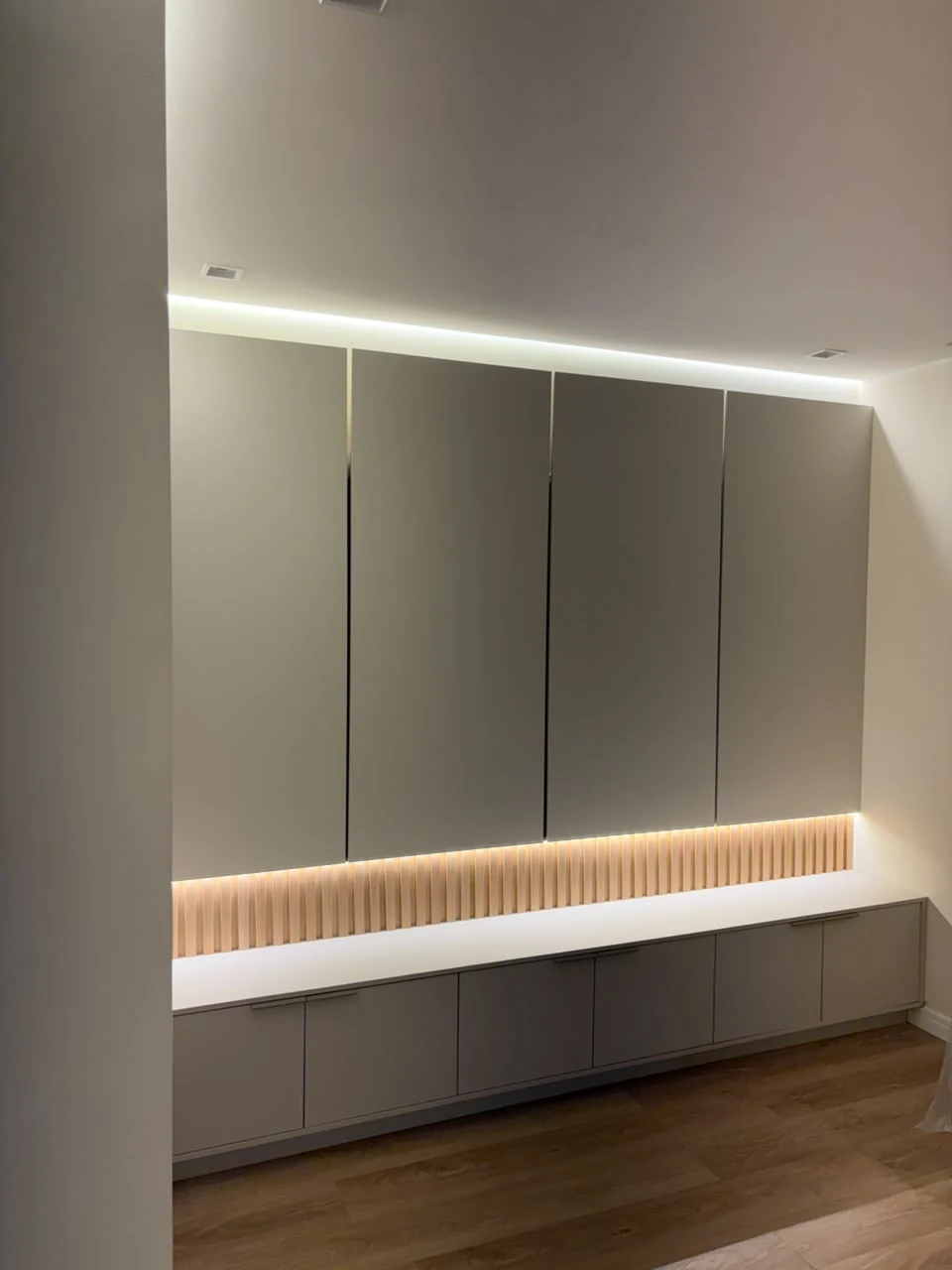 Painel com portas superiores, bancada, ripado e iluminação integrada
